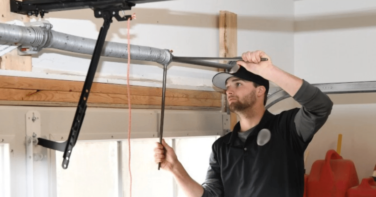 Technician replacing dual torsion springs on a garage door.