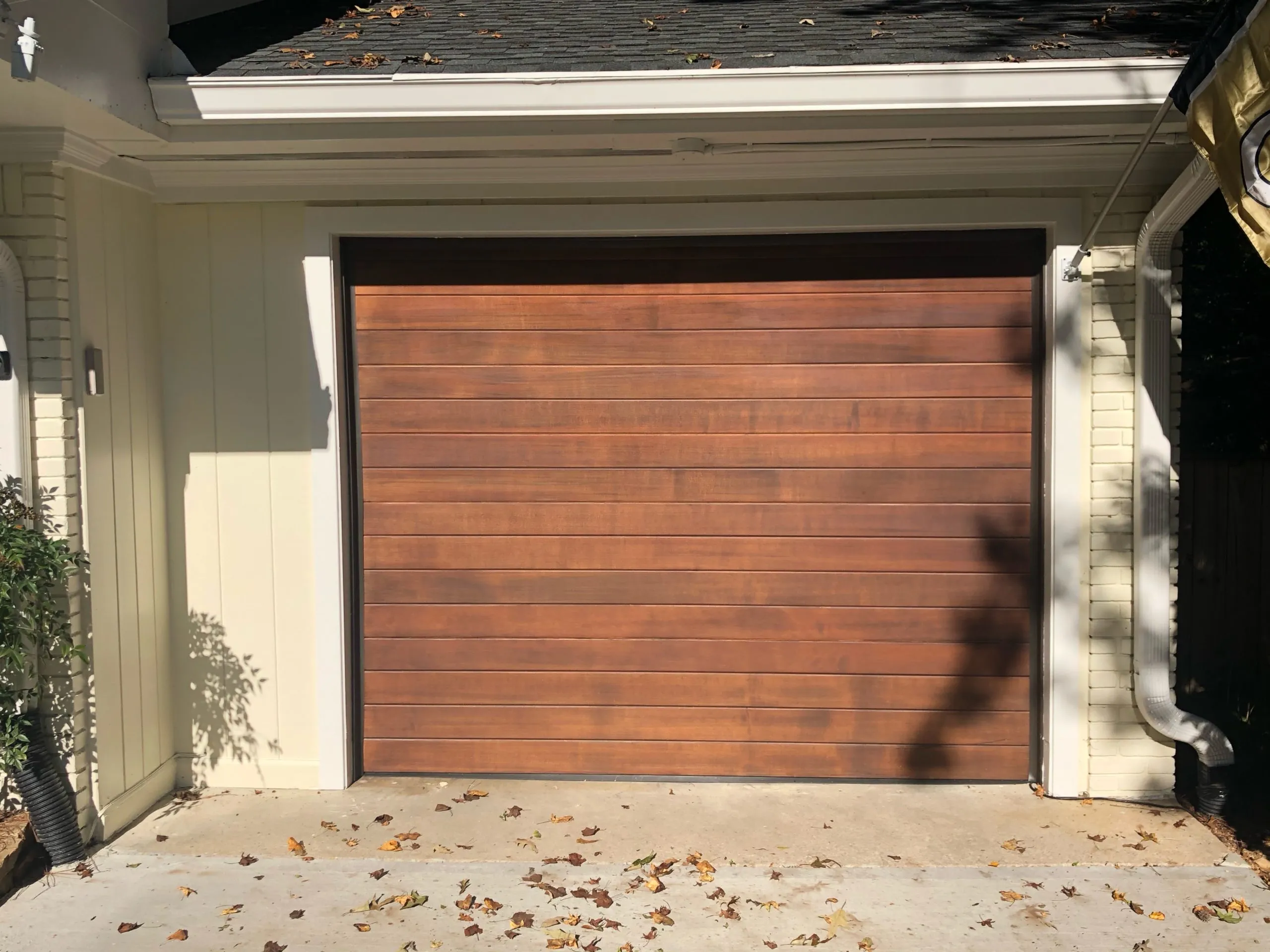 Cedar-finish wood-look composite garage door installed.